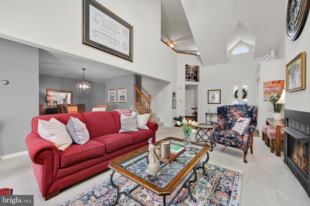 Living room with a red sofa, floral armchair, vaulted ceiling, and fireplace.