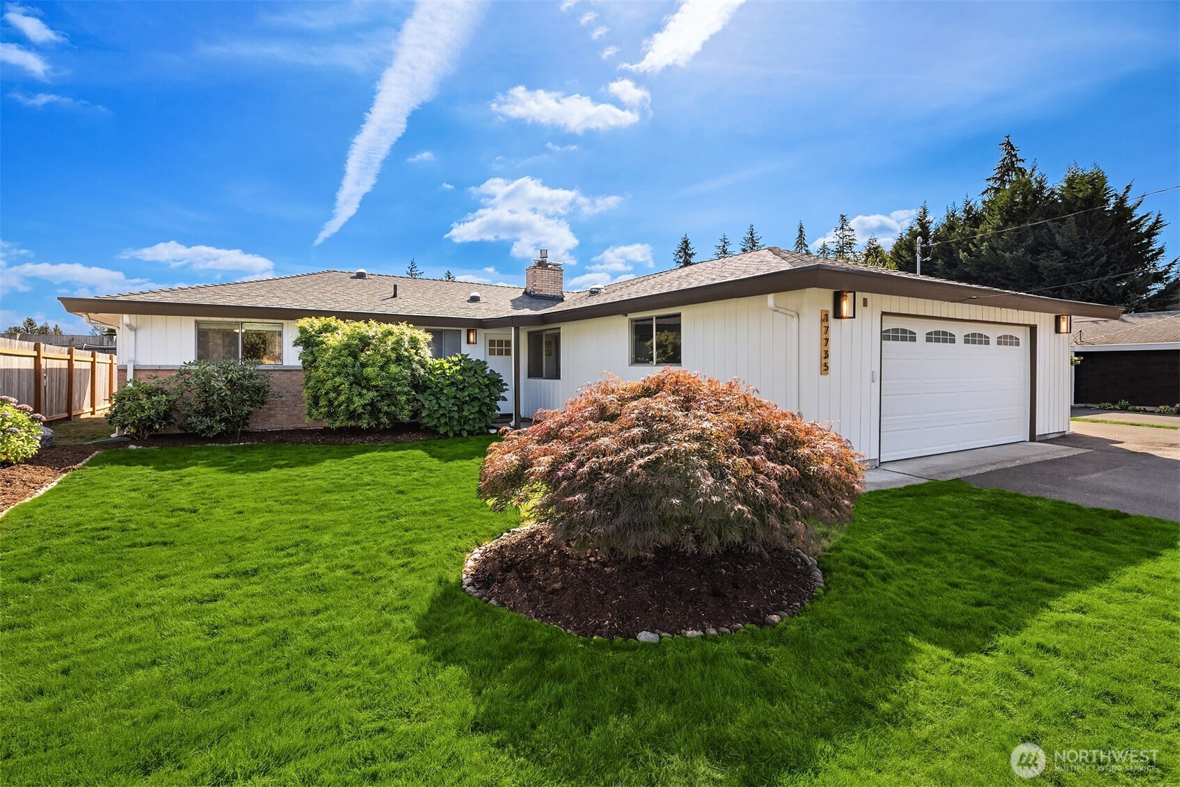 Single-story white house with an attached garage, broad green lawn, and Japanese maple in front.