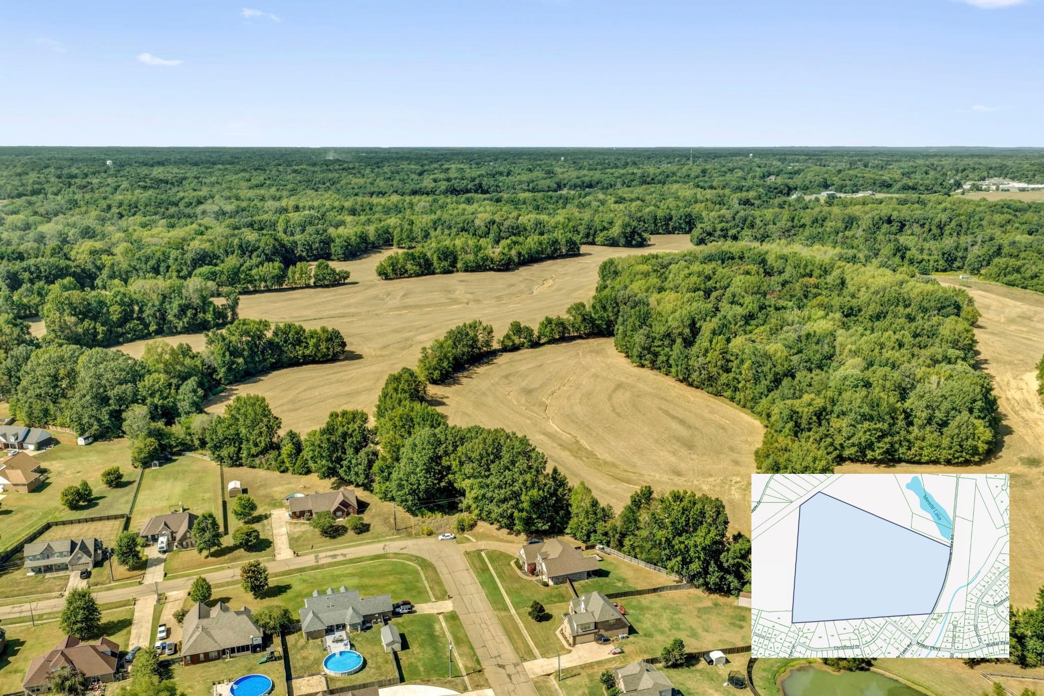 Aerial view of cleared fields bordered by woods, with nearby homes and a parcel map inset.