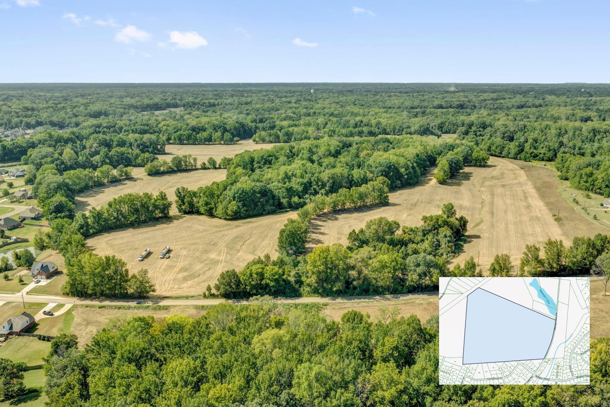 Aerial view of wooded land and broad cleared fields, with a parcel map inset.