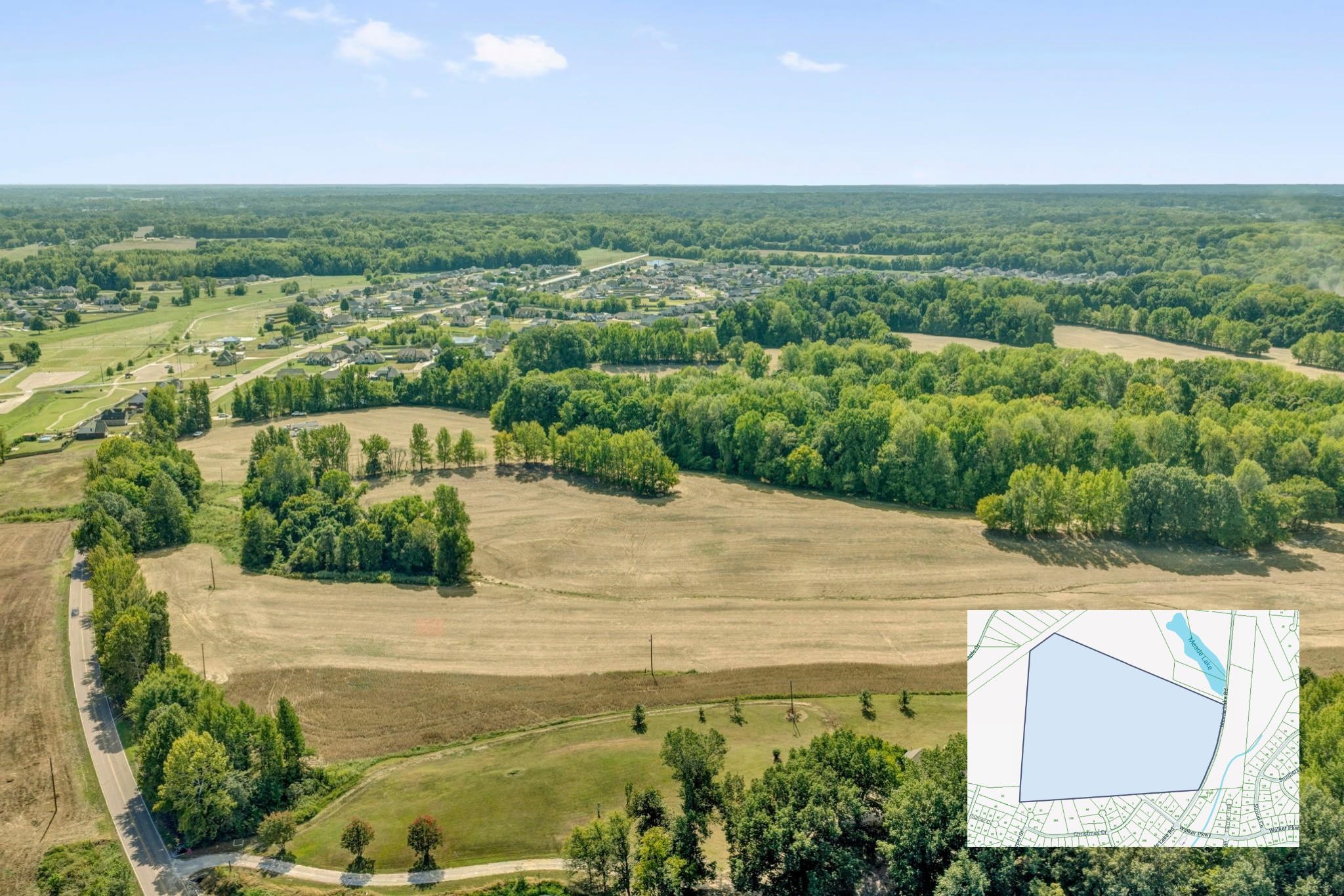 Aerial view of a large cleared parcel bordered by woods, with a parcel map inset.