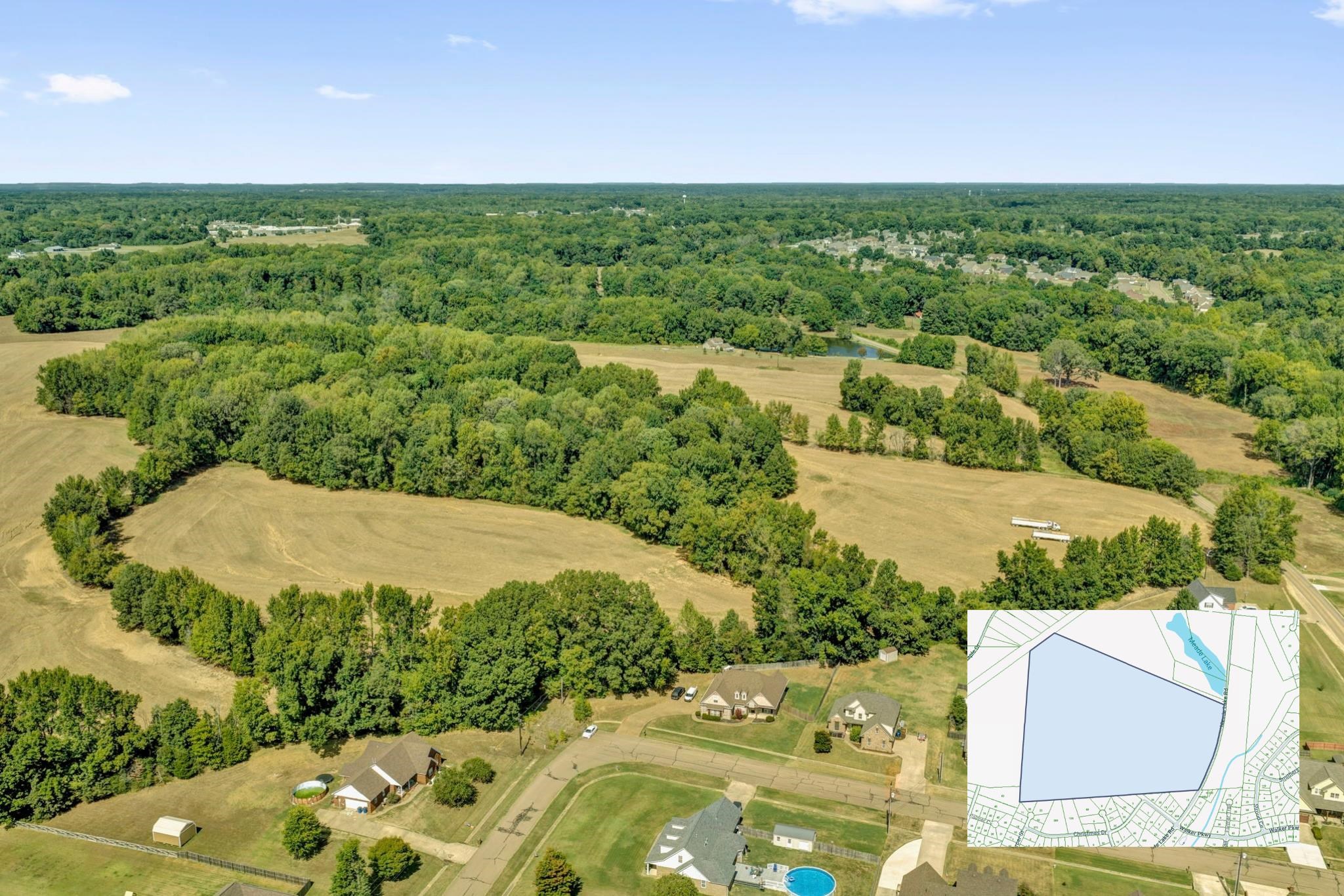 Aerial view of a large, tree-lined property with open fields and a parcel map inset.