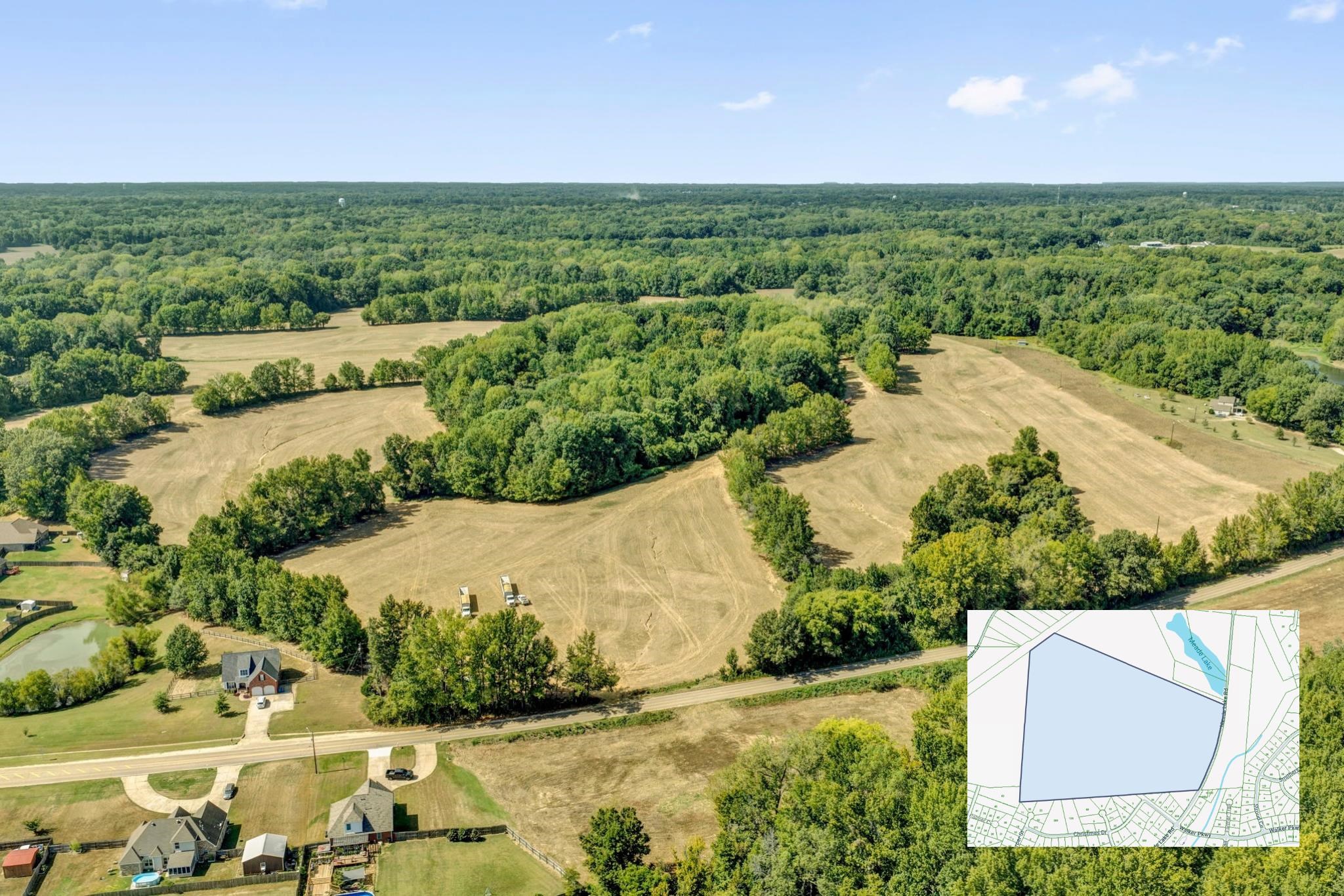 Aerial view of cleared fields and wooded land beside a road, with the parcel outlined on an inset map.