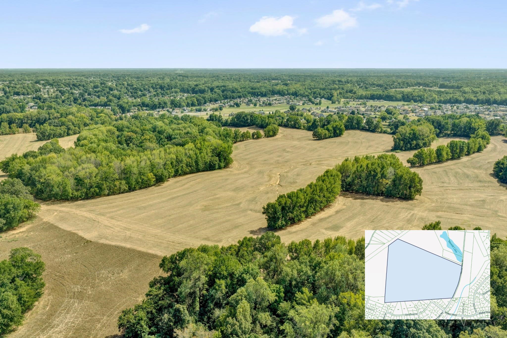 Aerial view of a broad cleared parcel surrounded by trees, with its boundaries shown on an inset map.