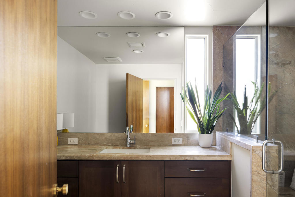 Bathroom vanity with a stone countertop, dark wood cabinetry, and a glass-enclosed shower.