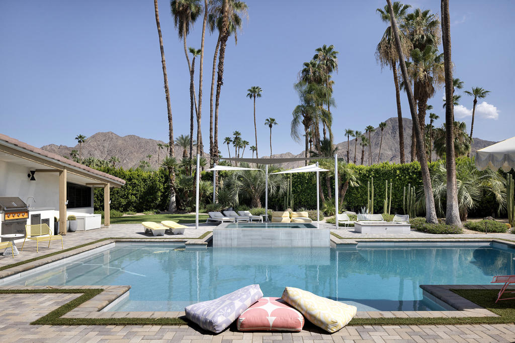 Backyard pool and raised spa framed by palm trees, lounge seating, and mountain views.