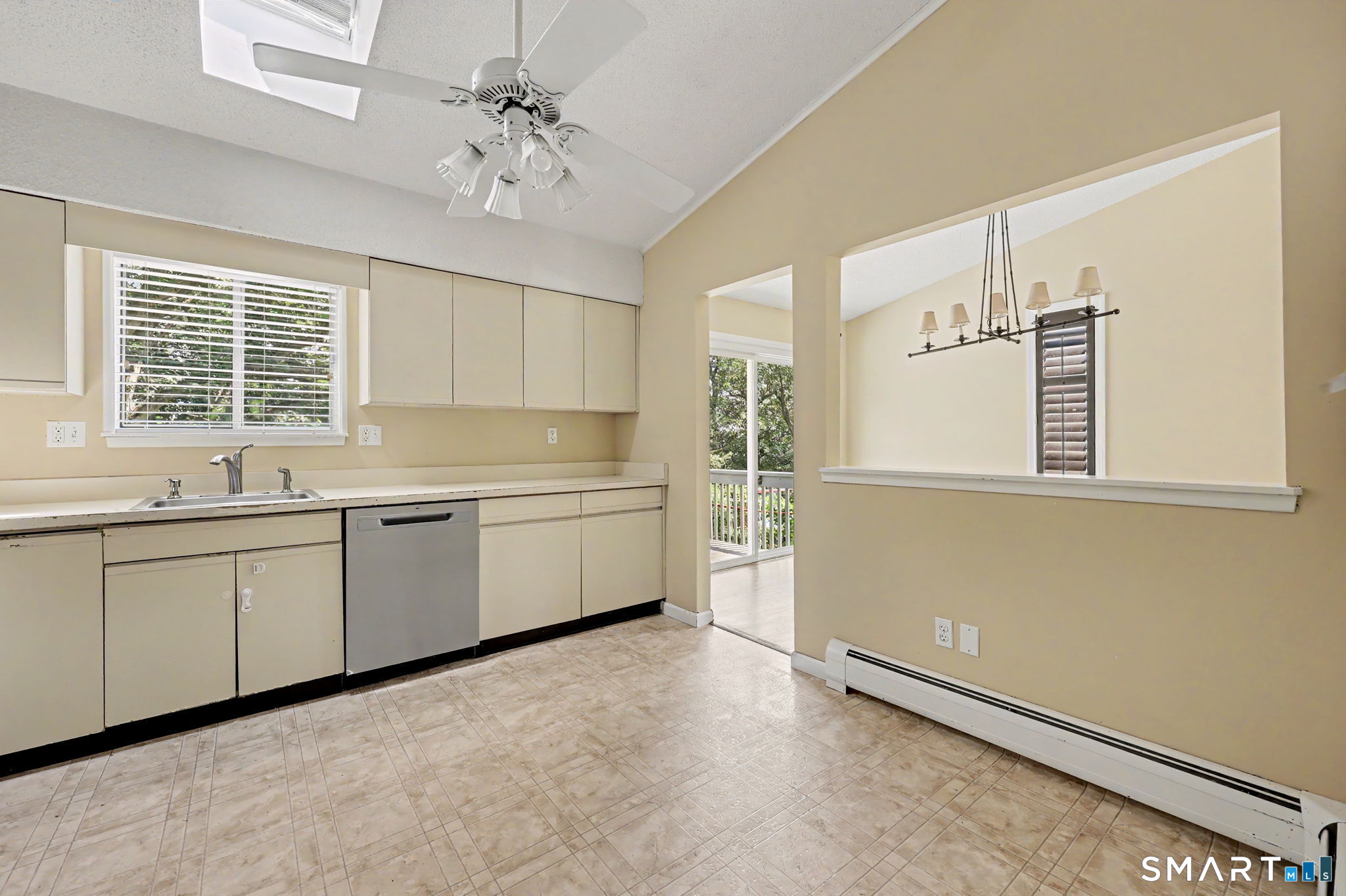 Kitchen with cream cabinets, patterned tile floor, and a pass-through to the dining area.