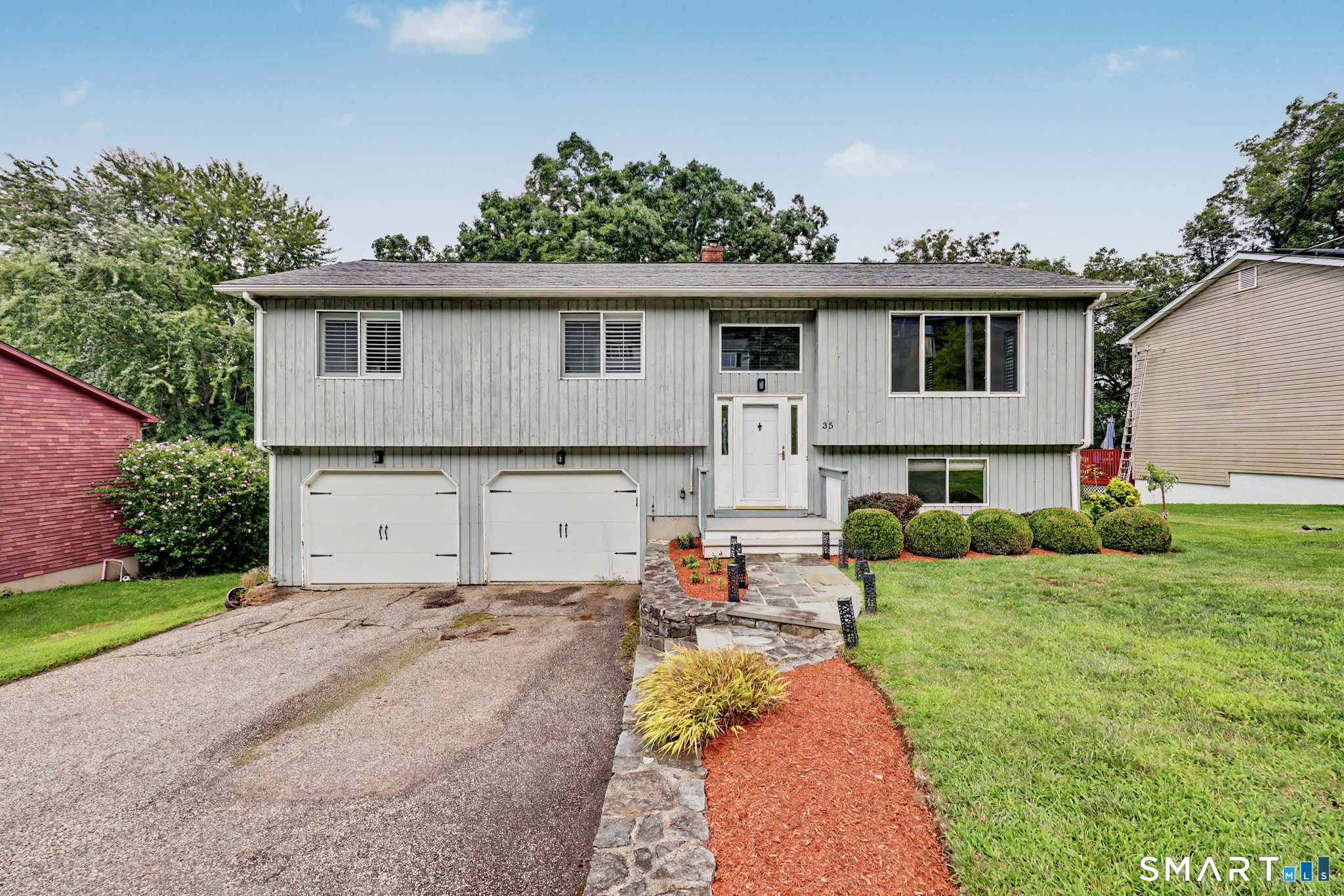 Gray split-level home with two garage doors and a stone walkway leading to the front entrance.