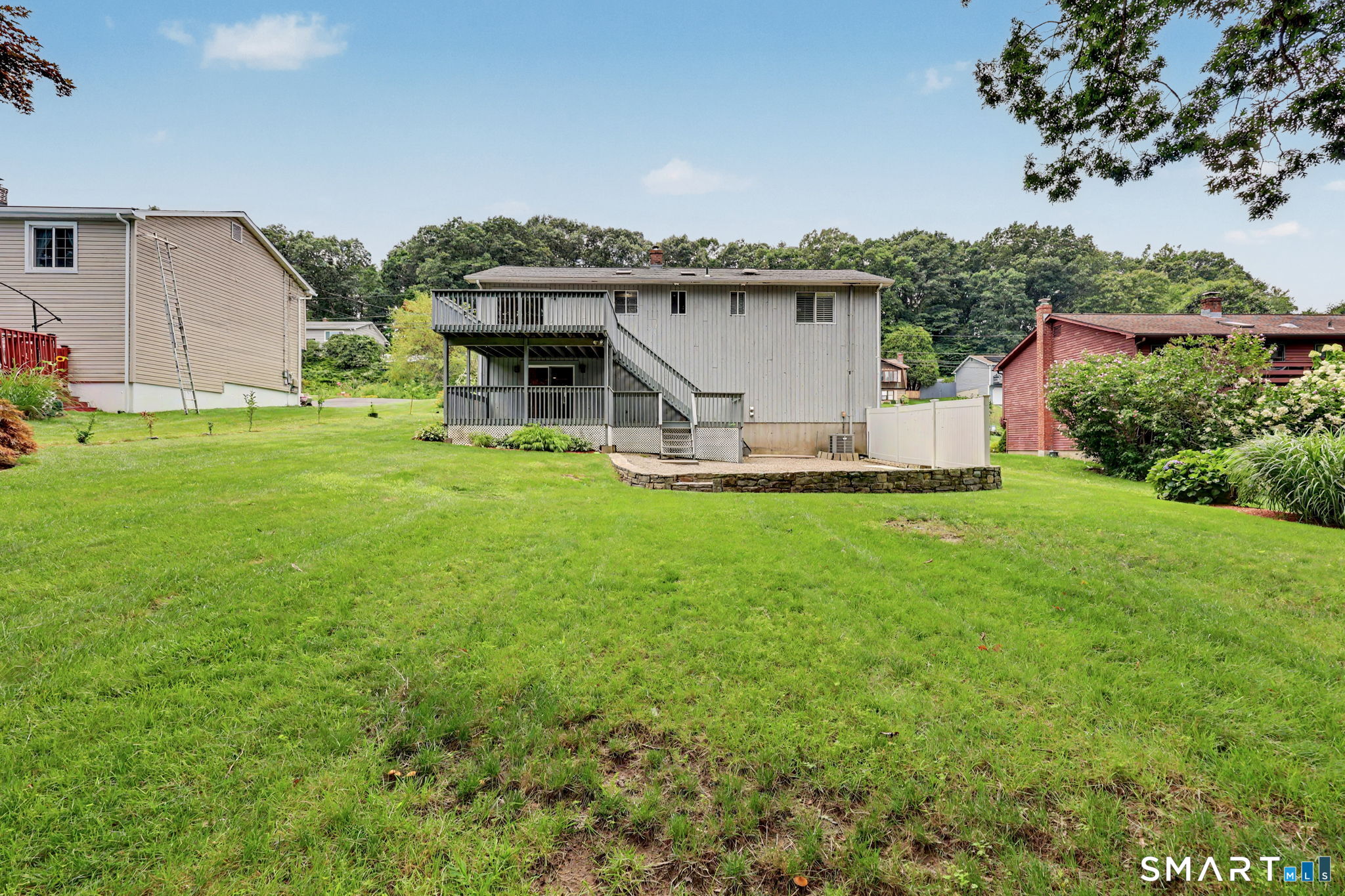 Rear of a raised home with a two-level deck and broad grassy lawn.
