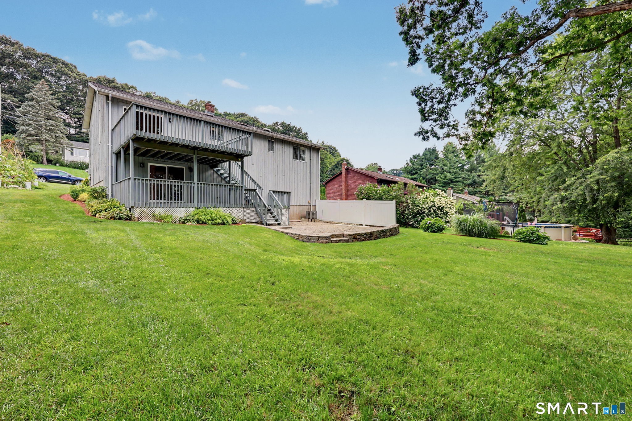 Rear of a gray two-story home with balconies, a sloping lawn, and a backyard pool.