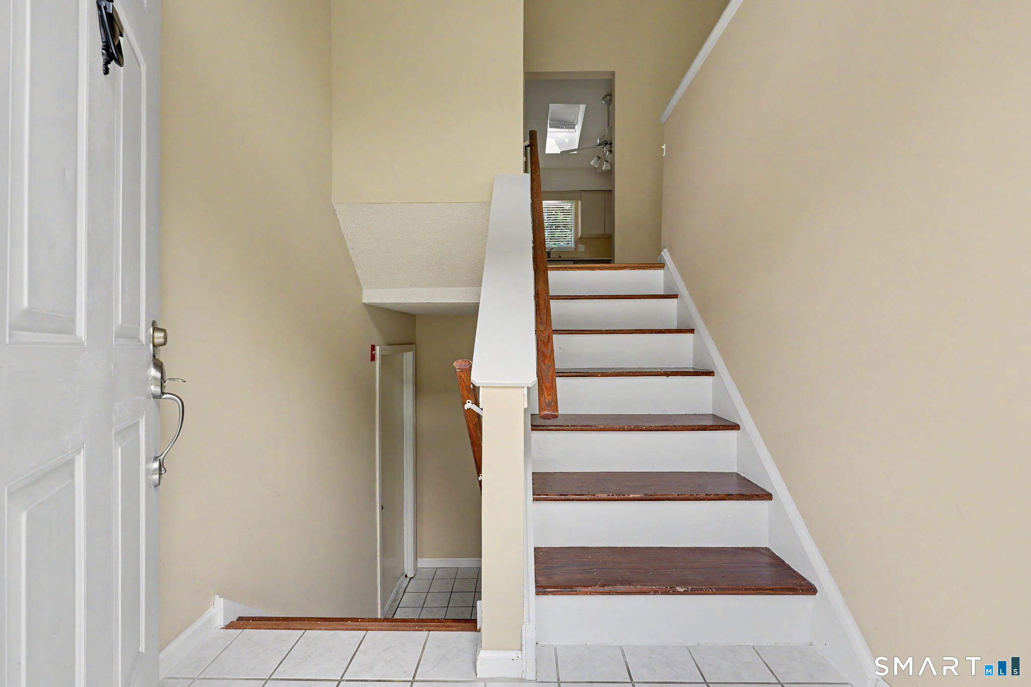 Entry hall with tiled floor and staircase with dark wood treads and white risers.