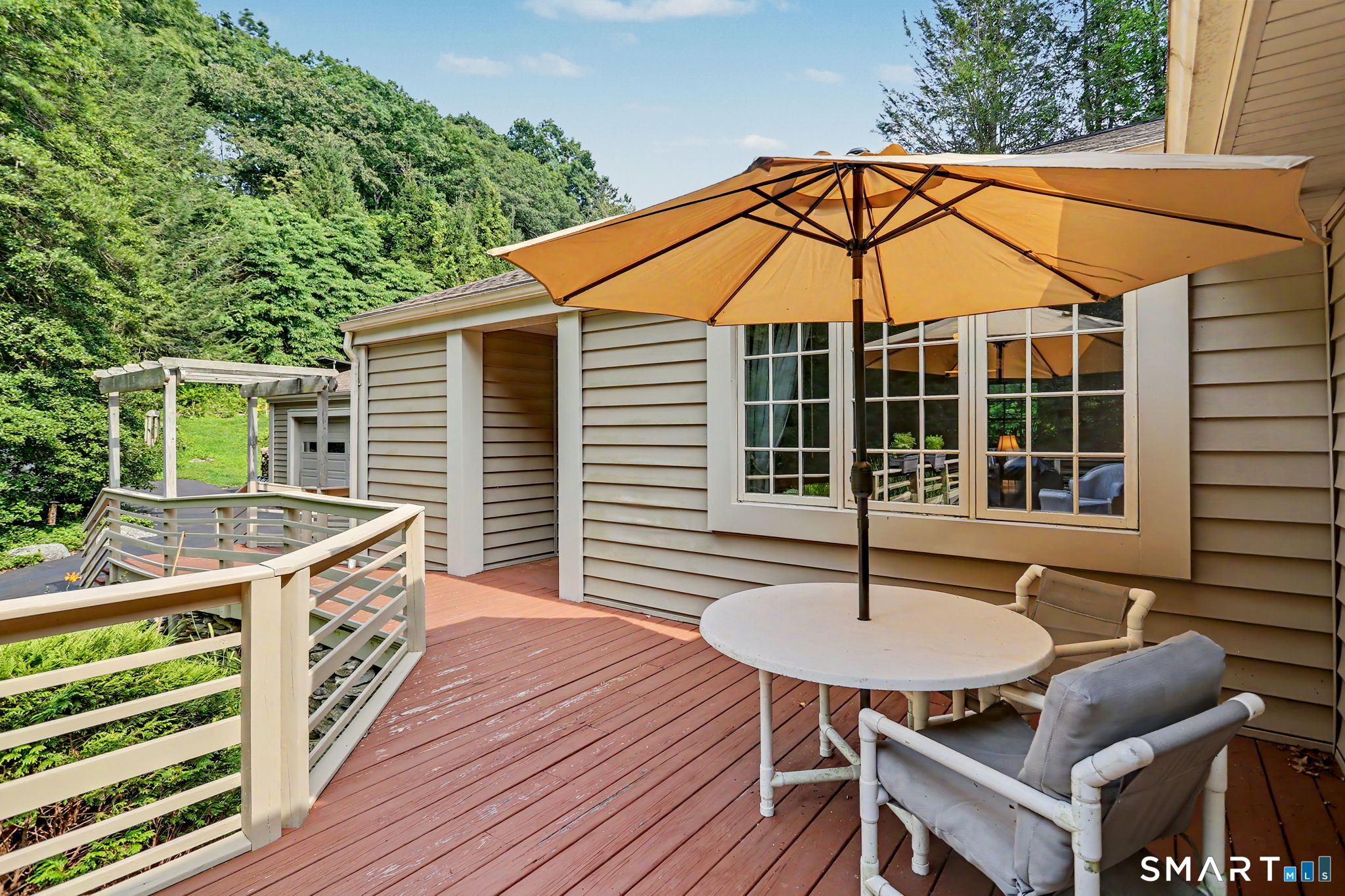 Deck with white railings, an orange umbrella, and patio seating beside the house.