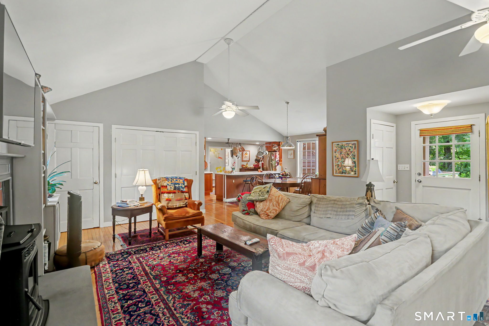 Vaulted living room with a large sectional sofa and colorful rug opening into the kitchen.