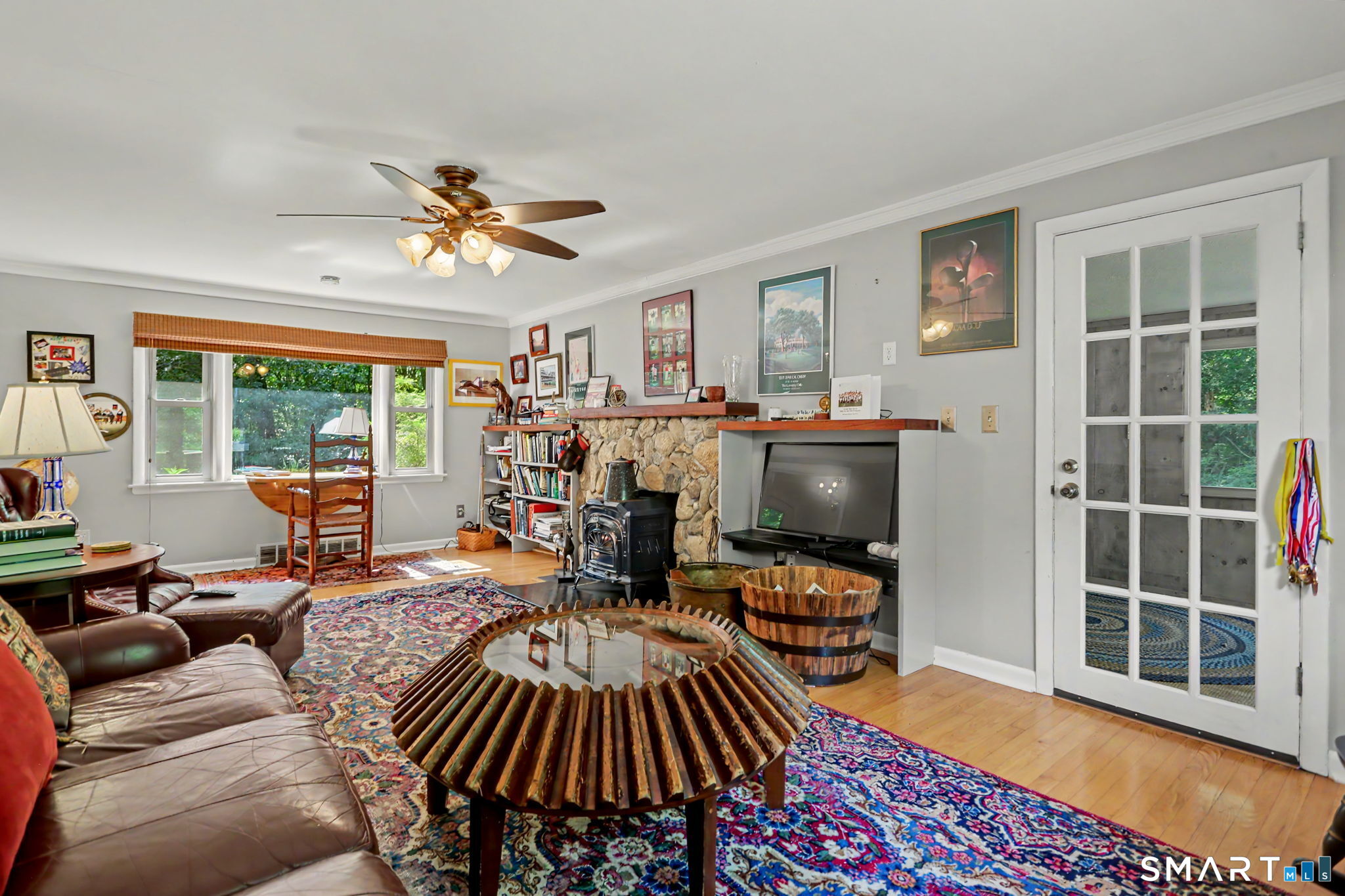 Living room with a stone fireplace, wood stove, leather seating, and colorful patterned rugs.