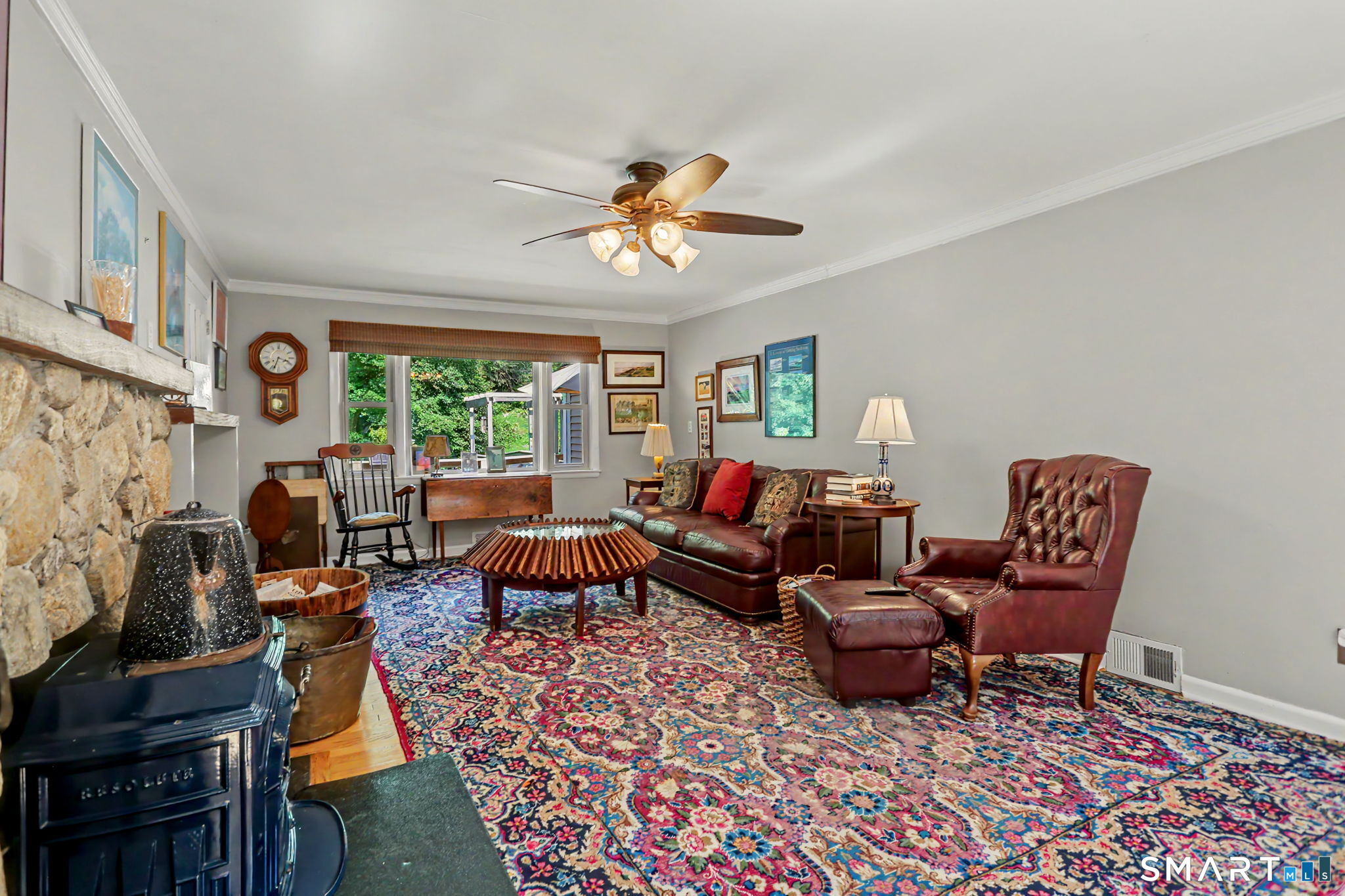 Living room with a stone fireplace, leather seating, and a colorful patterned rug.