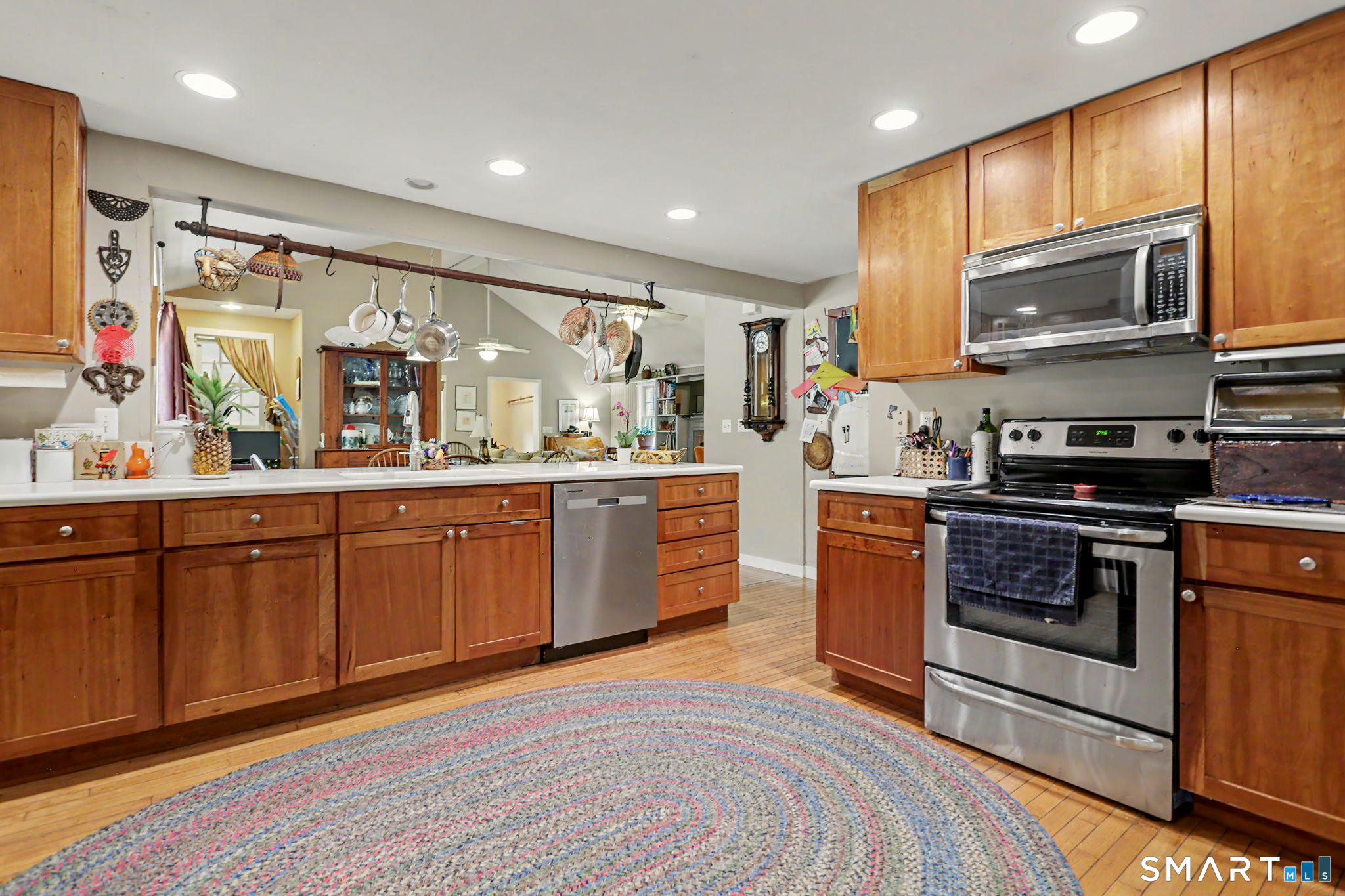 Kitchen with warm wood cabinets, stainless steel appliances, and a round braided rug.