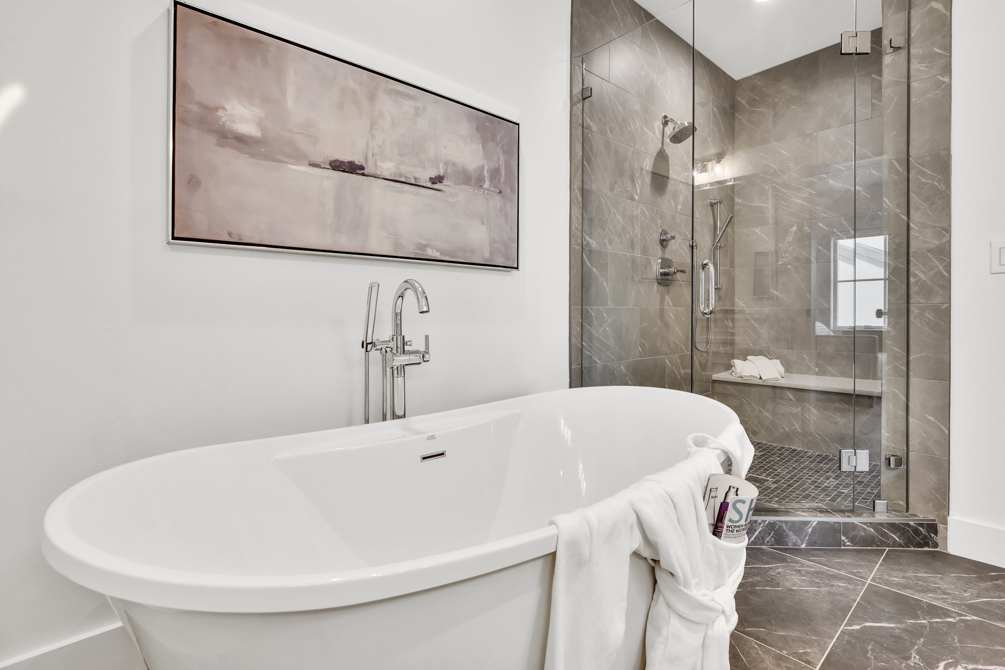 Modern bathroom with a freestanding soaking tub and glass-enclosed gray-tile shower.