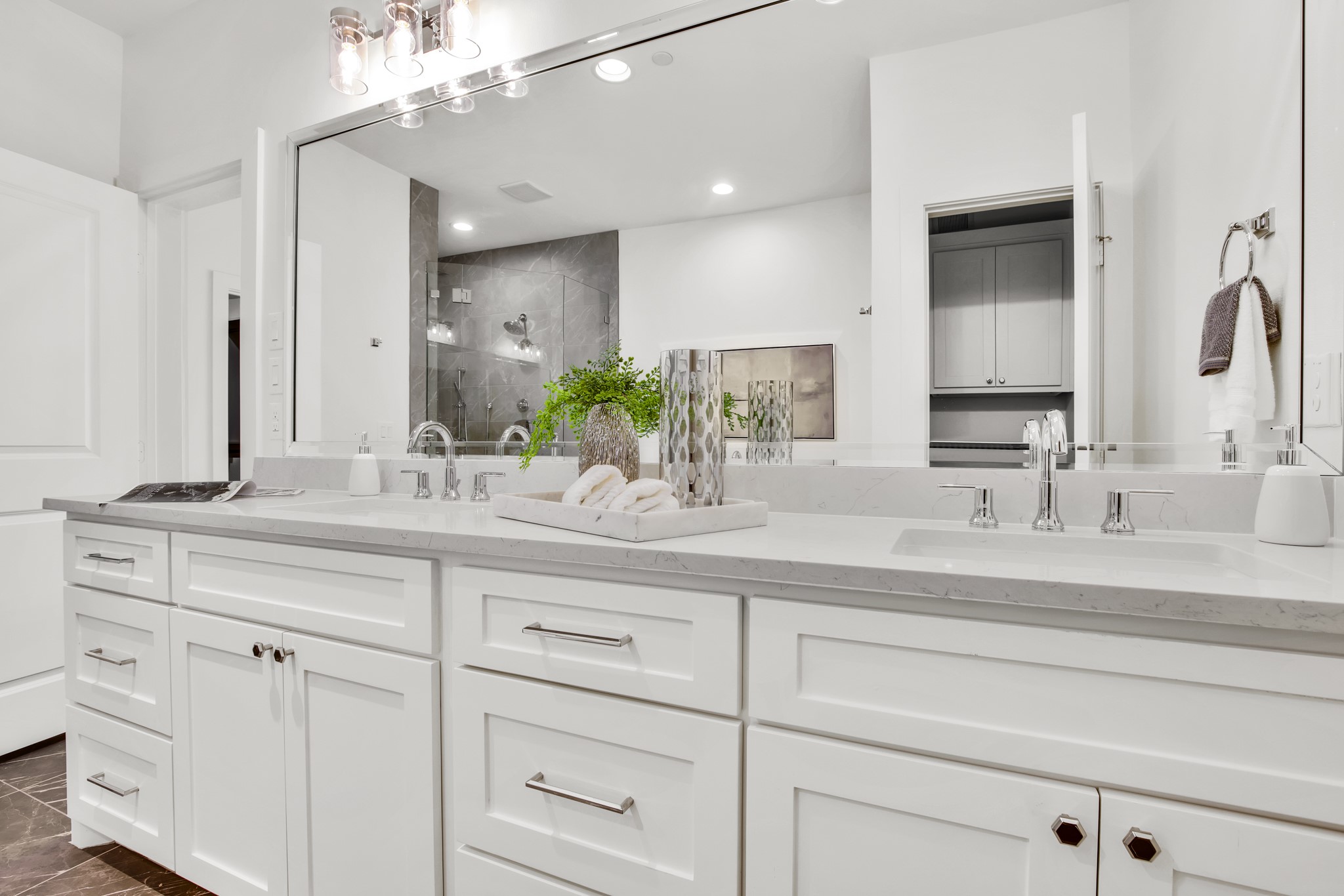 Bright bathroom with a white double vanity, marble countertop, and gray marble shower.