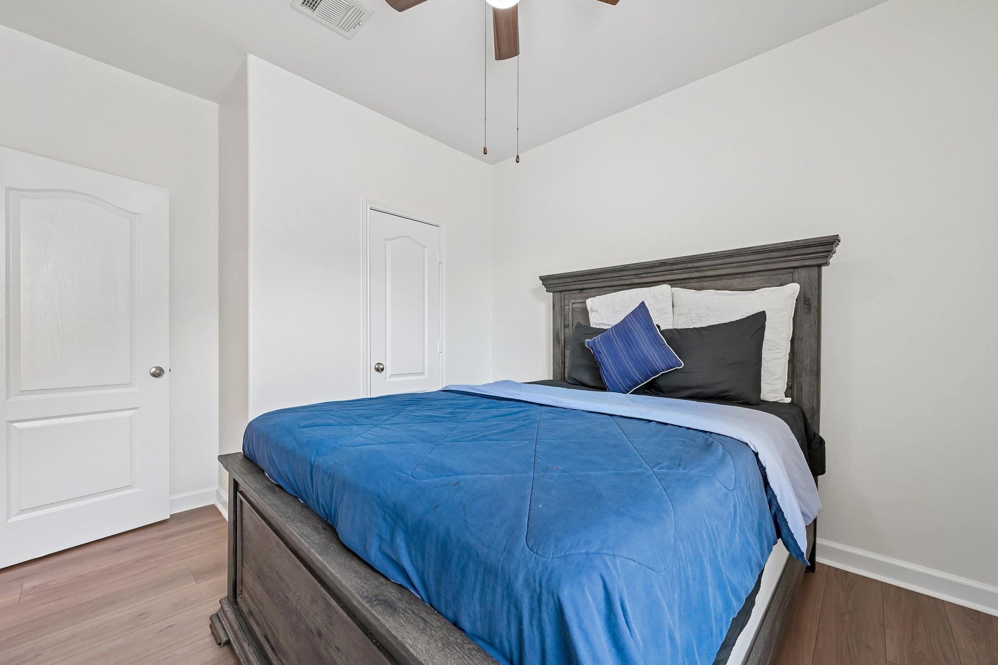 Bedroom with a large dark wood bed dressed in blue bedding and contrasting pillows.