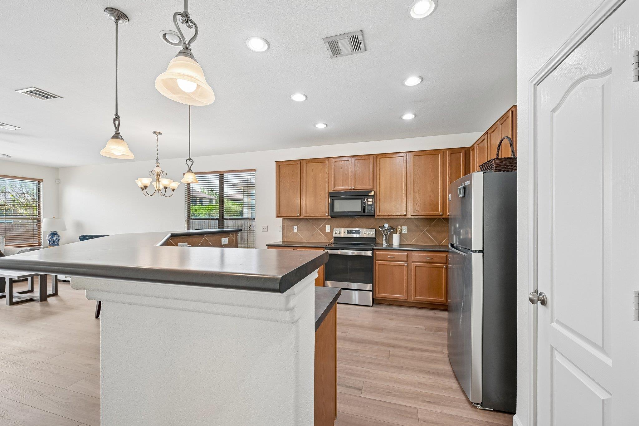 Kitchen with a large island, warm wood cabinets, and stainless steel appliances.
