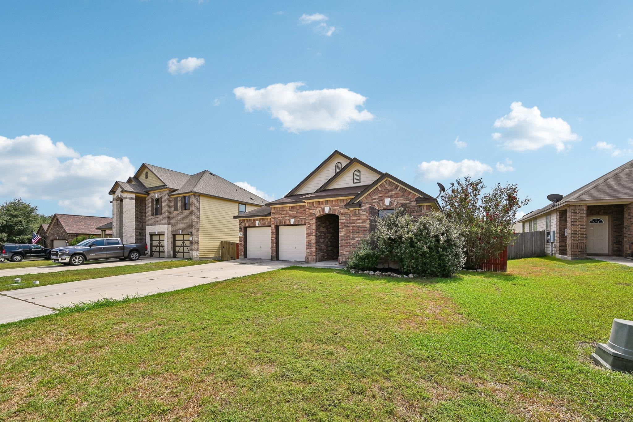 Brick house with an attached two-car garage, driveway, and broad front lawn.