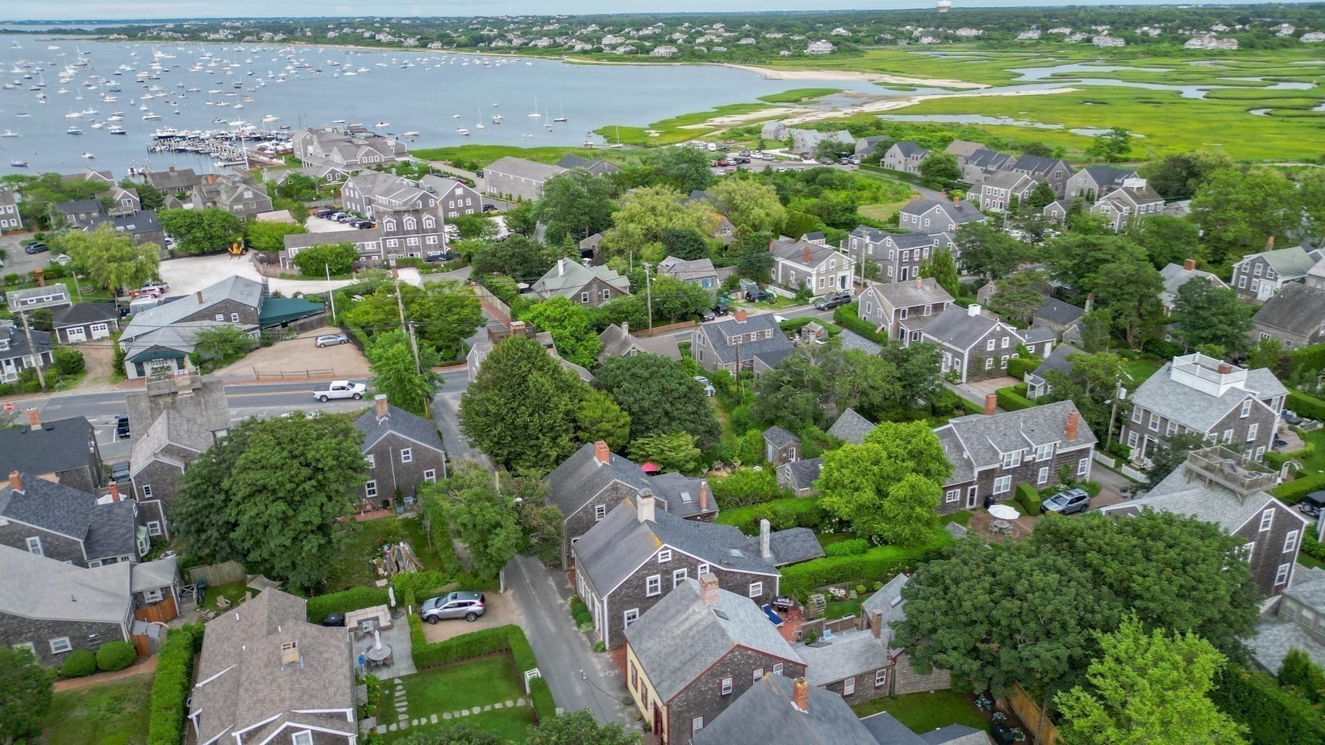 Aerial view of Nantucket homes, harbor boats, and coastal wetlands.