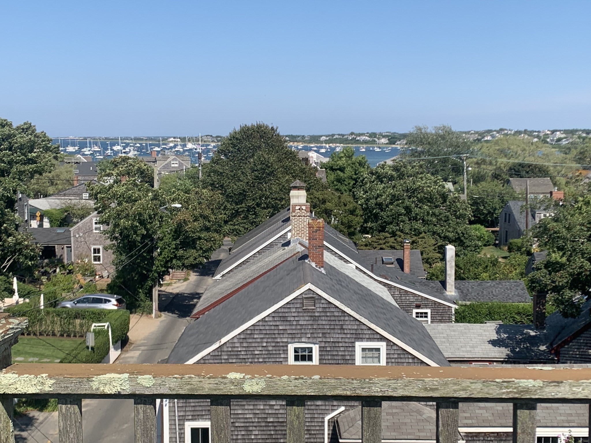 Elevated view over Nantucket rooftops toward a harbor filled with sailboats.
