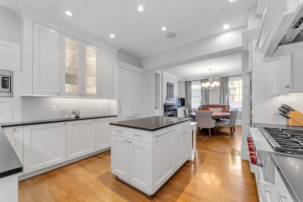 Bright white kitchen with a dark-topped island, stainless range, and adjoining dining area.