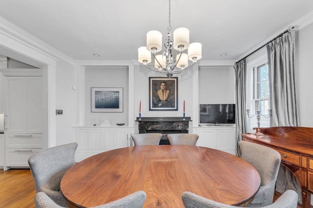 Dining room with a round wooden table, chandelier, and fireplace