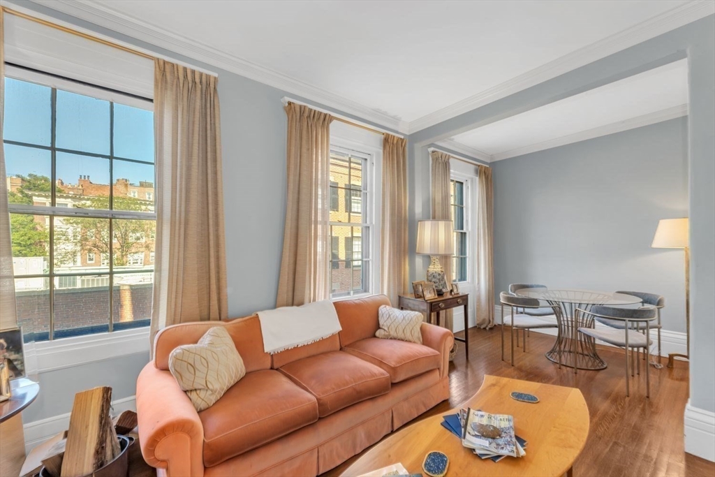 Living room with a peach sofa, large curtained windows, and a round dining table.