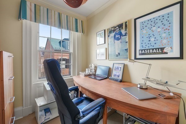 Furnished home office with a curved wooden desk, black chair, and framed baseball memorabilia.