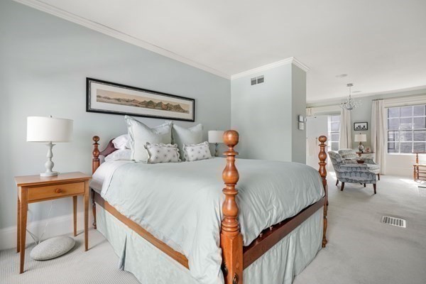 Bedroom with a wooden four-poster bed and a sitting area beside large windows.