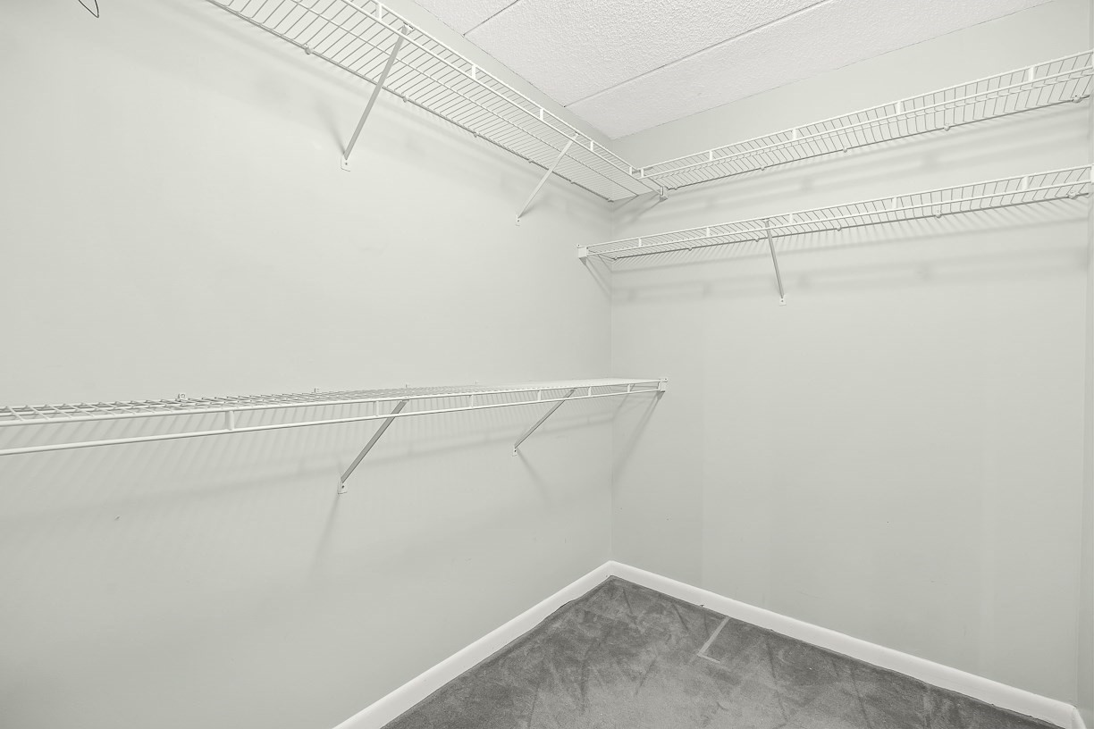 Empty walk-in closet with extensive white wire shelving and gray carpet.