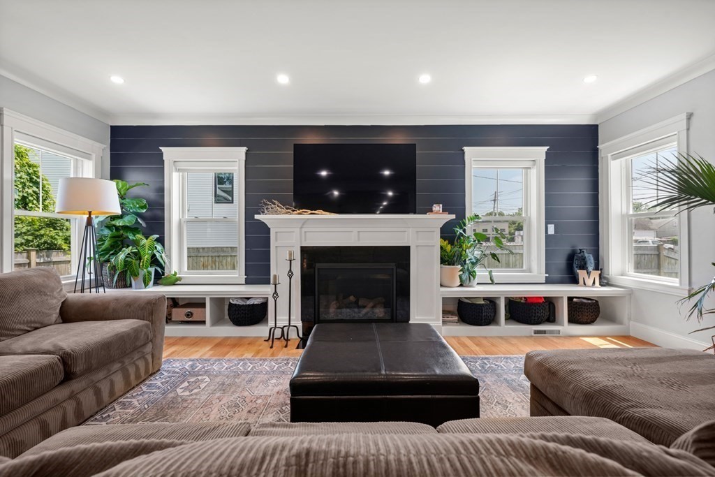 Living room with a white fireplace against a navy paneled wall and built-in window seats.