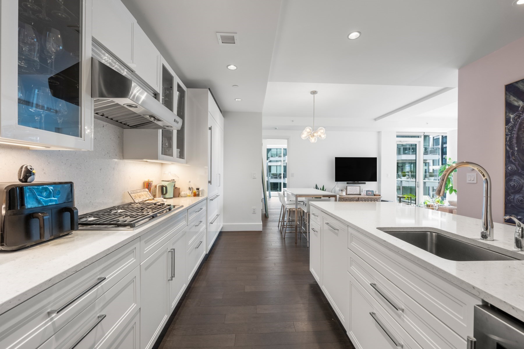 Modern white kitchen with a large island and open views into the dining and living area.