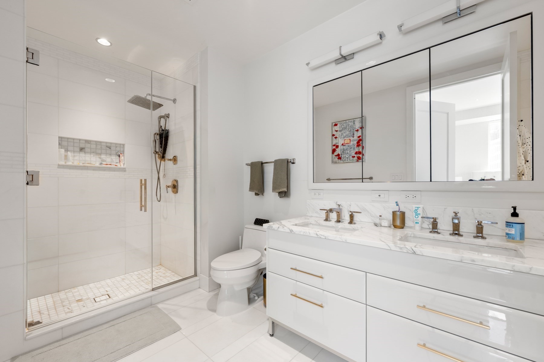 Modern bathroom with a glass walk-in shower and marble double vanity.