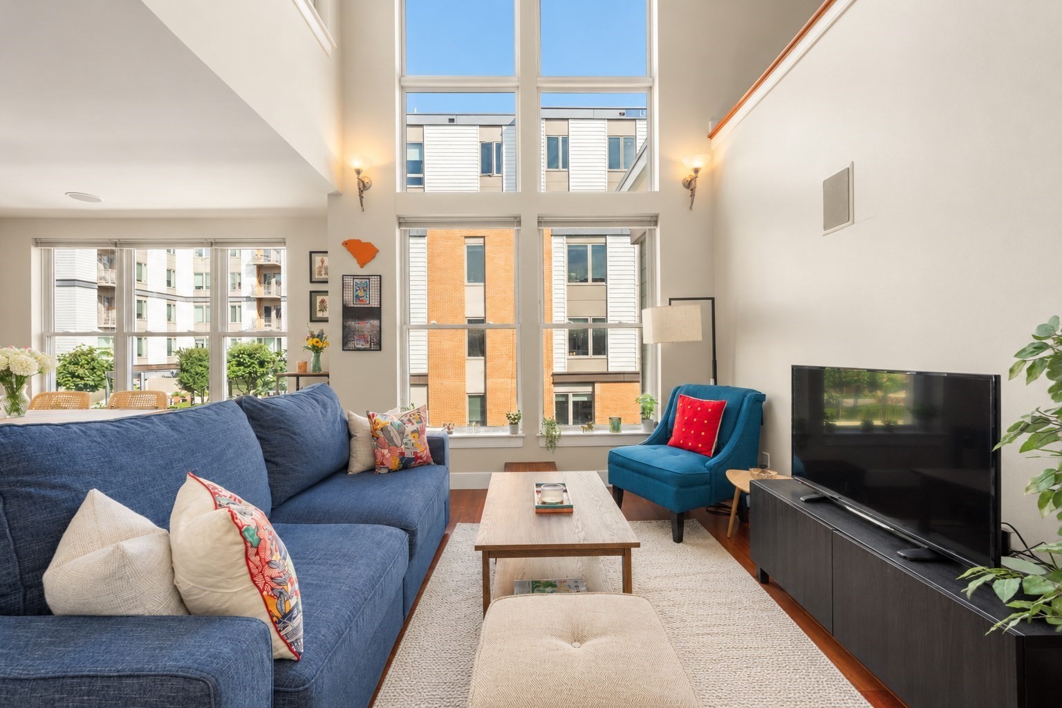 Living room with a blue sofa, teal armchair, and tall double-height windows.