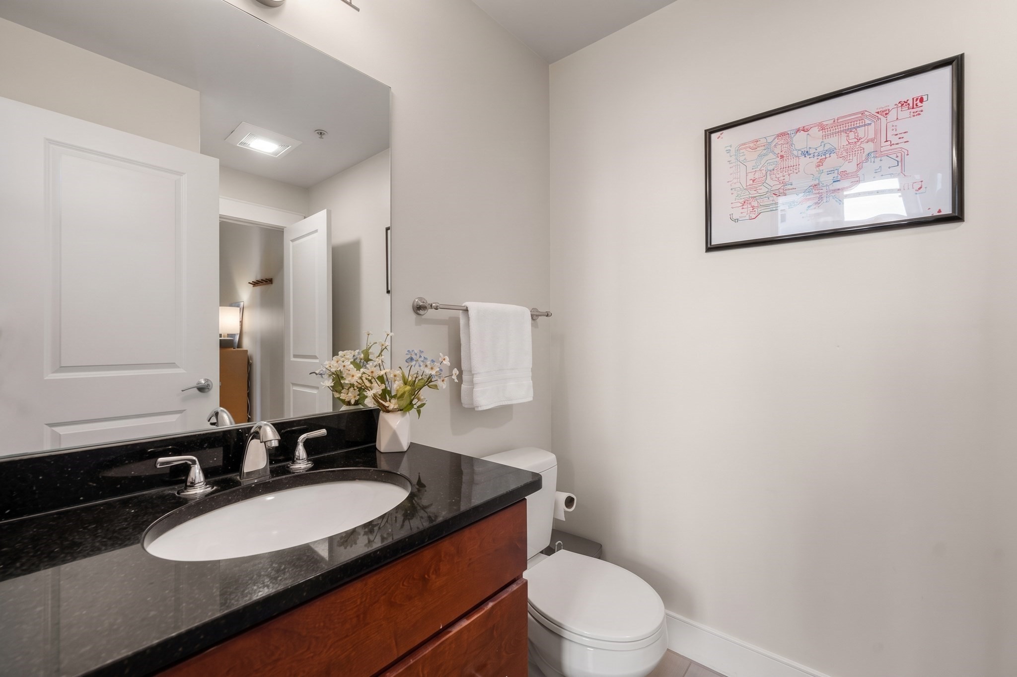 Bathroom with a granite vanity, wood cabinetry, and framed artwork above the towel bar.