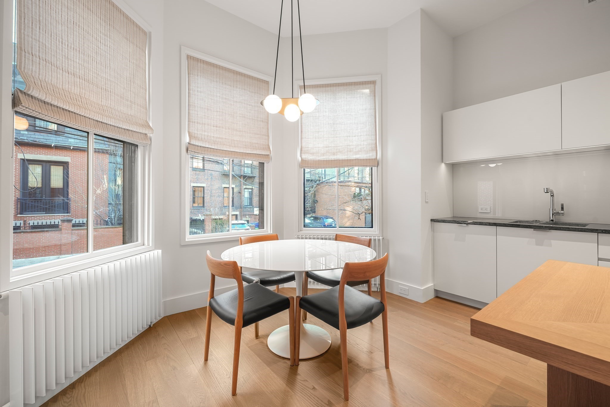 Modern kitchen and dining area with a round table, four chairs, and large windows.