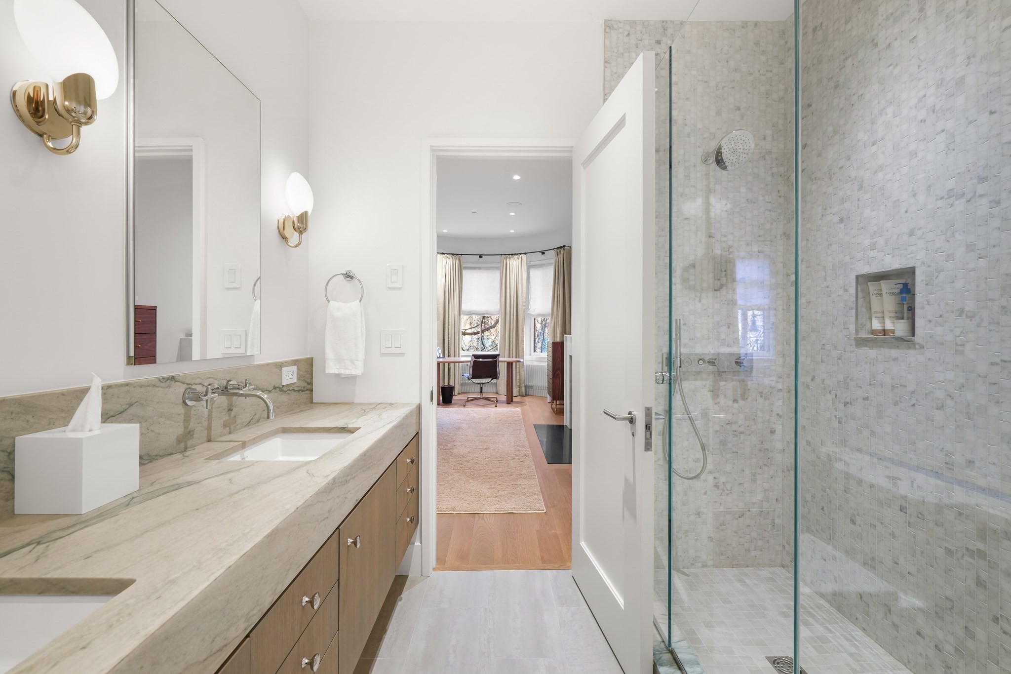 Modern bathroom with a marble double vanity and glass-enclosed mosaic-tile shower.