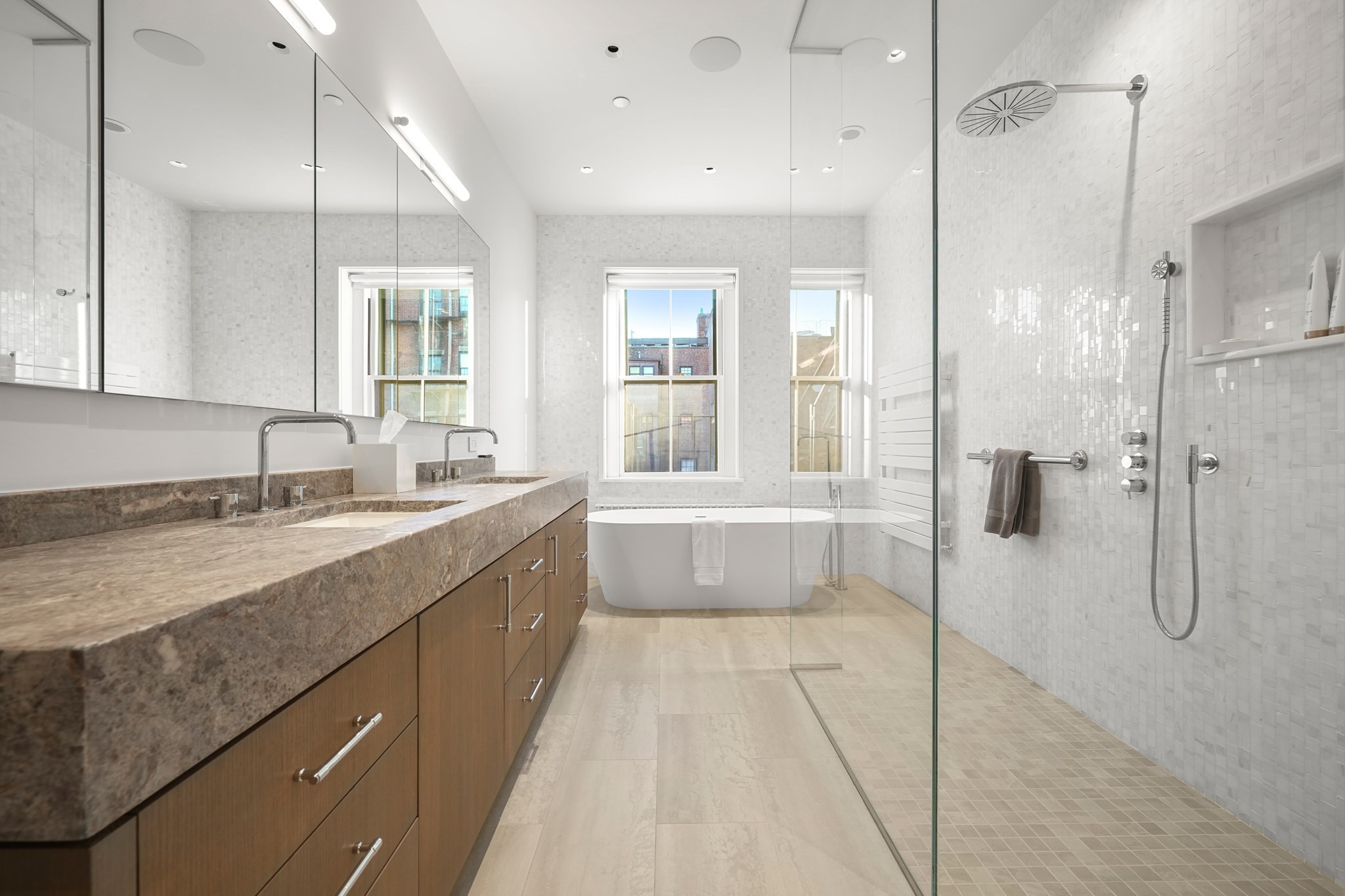 Modern bathroom with a stone double vanity, freestanding tub, and glass-enclosed shower.