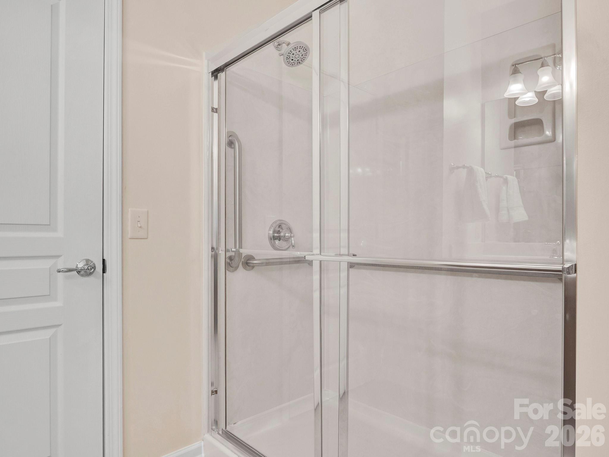 Bathroom shower with clear glass doors, chrome fixtures, and a built-in wall niche.