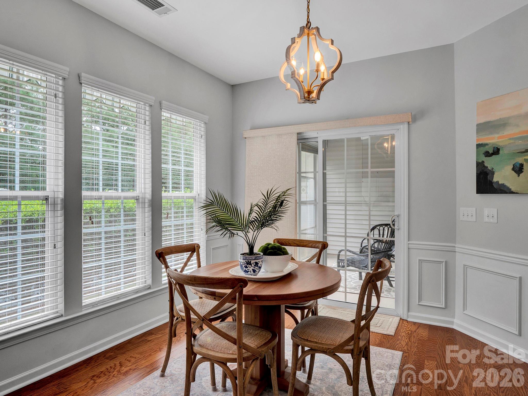 Dining room with a round wooden table, four chairs, and a sliding glass door to the patio.