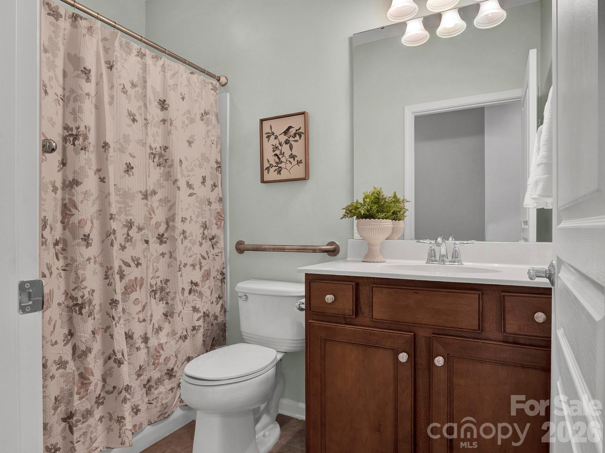 Bathroom with dark wood vanity, large mirror, and floral shower curtain.