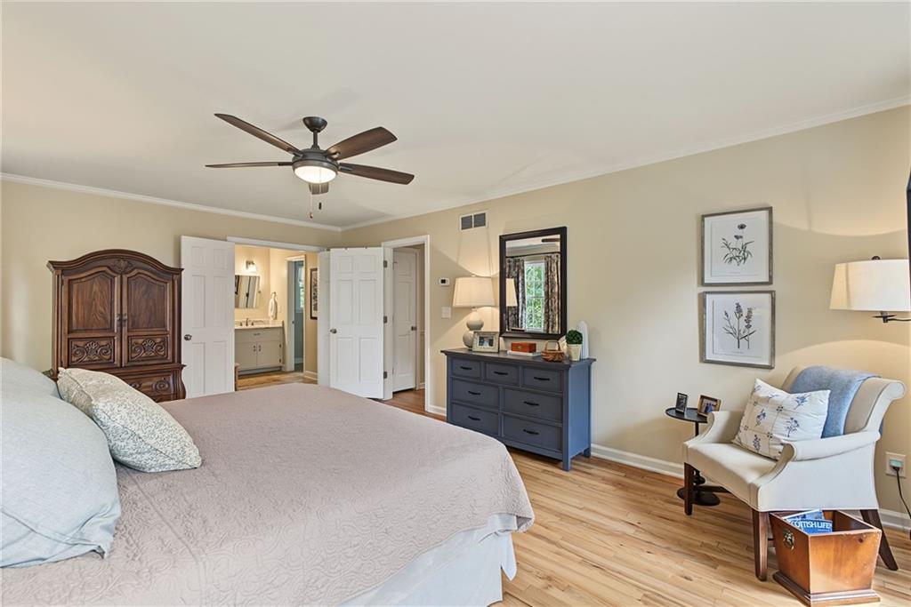 Furnished bedroom with a large bed, carved wooden armoire, blue dresser, and doorway to an adjoining bathroom.