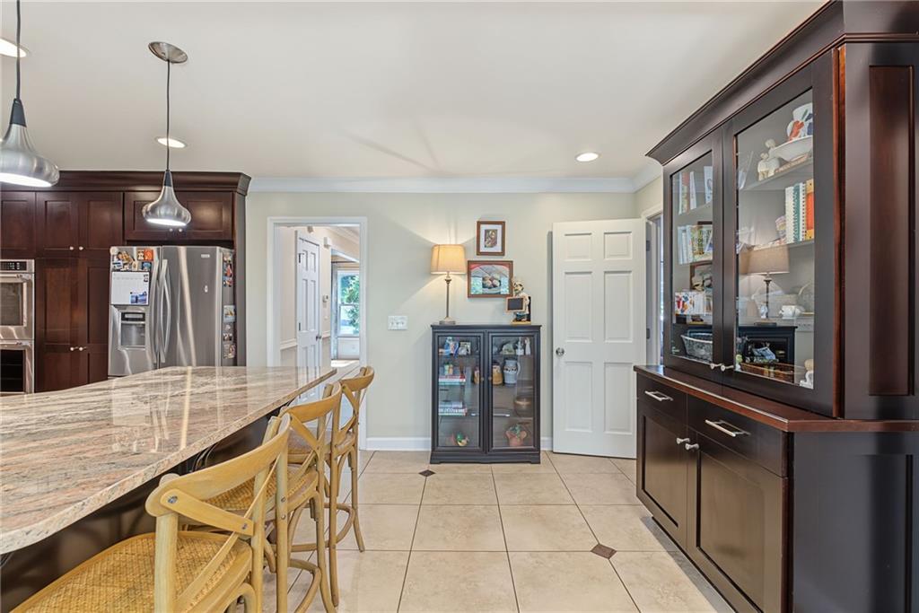 Kitchen with a granite island, wooden bar stools, dark cabinetry, and glass-front storage cabinets.