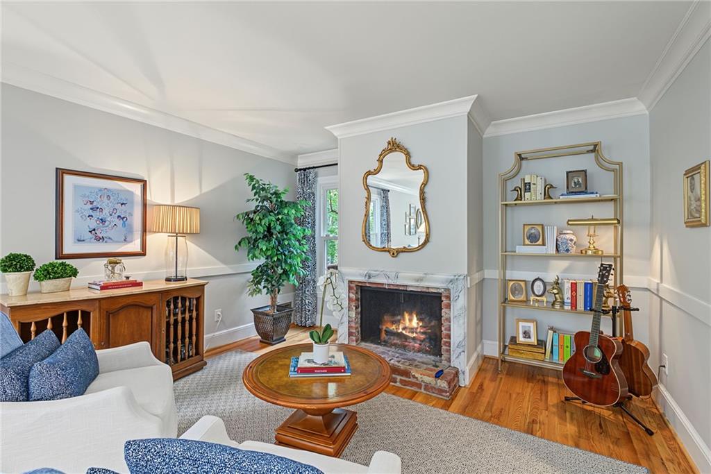 Living room with a lit fireplace, built-in shelves, hardwood floors, and a white sofa.