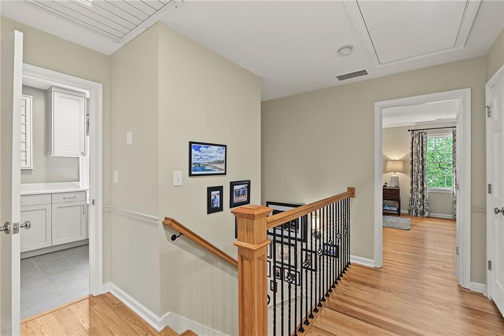 Interior landing with a wood-and-black-metal staircase and doorways to a tiled bathroom and bright bedroom.