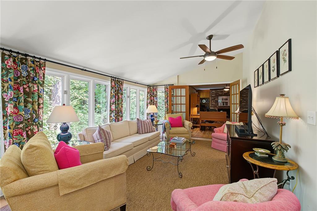 Furnished living room with large windows, floral curtains, and pink accent chairs.