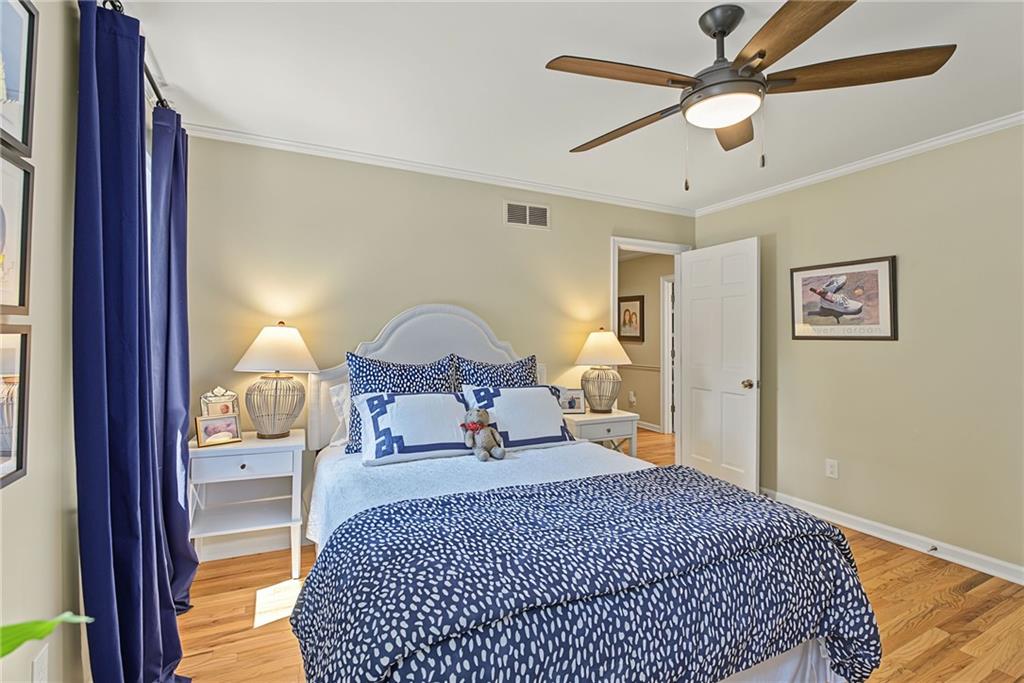 Bedroom with blue-and-white bedding, a pale blue headboard, hardwood floors, and a ceiling fan.
